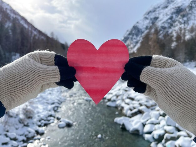 A woman holds a paper heart with a beautiful winter landscape in the background St Valentine symbol