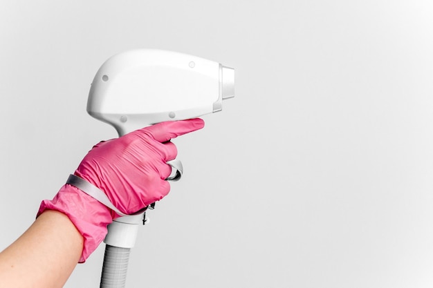 A woman holds a part of an epilator in her hands on a light background Laser hair removal Body care