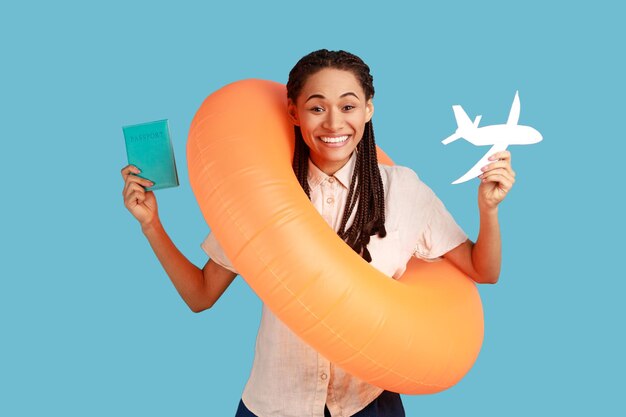 Woman holds passport with boarding pass tickets and paper plane feels excited about future trip