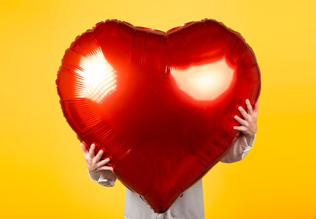 Woman holds red balloon of very big heart shape. Valentines day concept