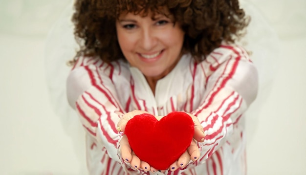 A woman holds a red heart in her hands.