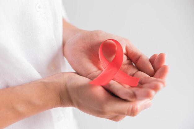 A woman holds a red ribbon in her hand Show the meaning of World AIDS Day          person