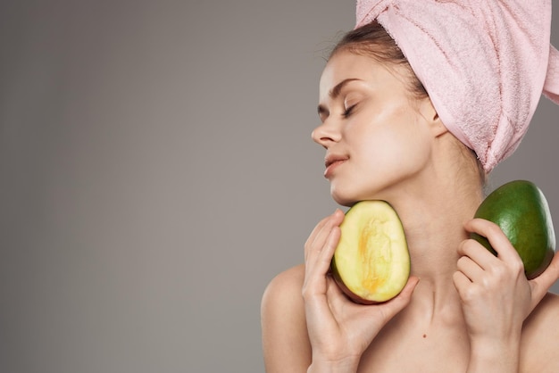 Photo woman holds a ripe mango in her hand bare shoulders with a towel on her head