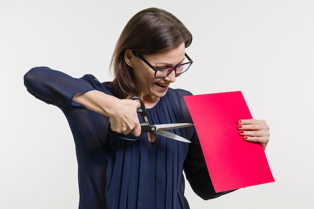 Woman holds scissors and a sheet of paper, cuts paper.