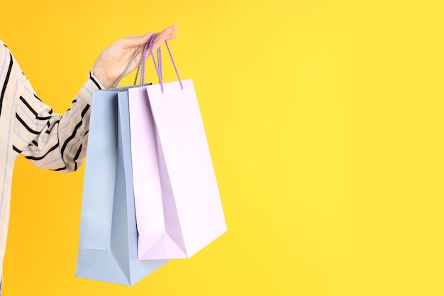 Woman holds shop bags on a yellow background