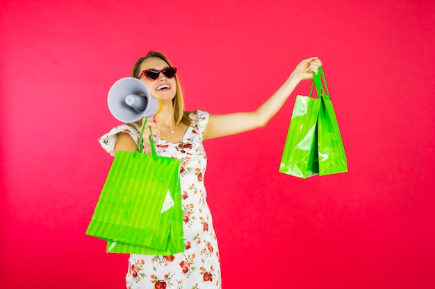 Woman holds shopping bags and megaphone in studio