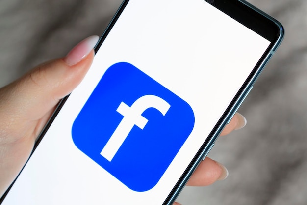 La donna tiene uno smartphone con l'applicazione facebook sullo schermo facebook è un'app di condivisione di foto per smartphone 13 marzo 2022 mogilev bielorussia