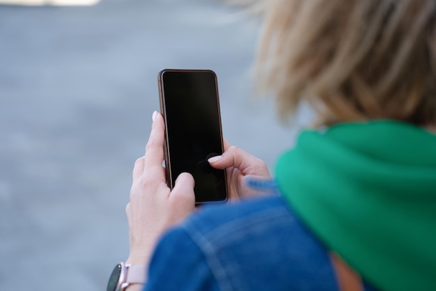 La donna tiene lo smartphone in mano sull'app mobile di strada e sul concetto di chat