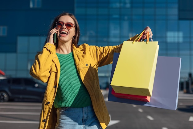 Woman holds smartphone and shopping paper bags