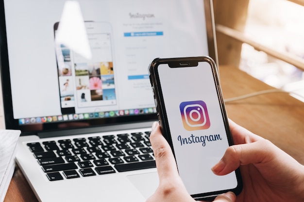 A woman holds an smartphone with instagram application on the screen at cafe.