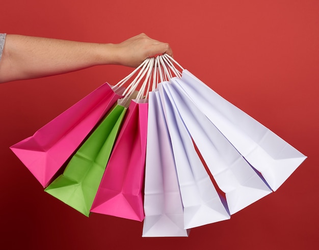 Woman holds stack of paper bags on red space