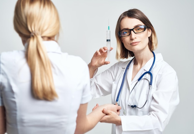 A woman holds a syringe in her hand and a female patient in a white tshirt is frightened model