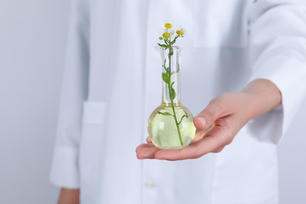 Woman holds test tube with flower close up