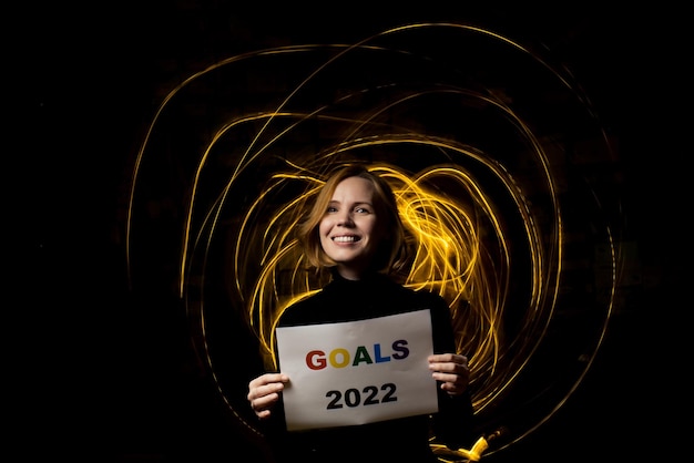 A woman holds the text Goals 2022 against a dark background with moving light