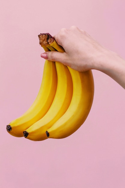 Woman holds three yellow bananas in her hand