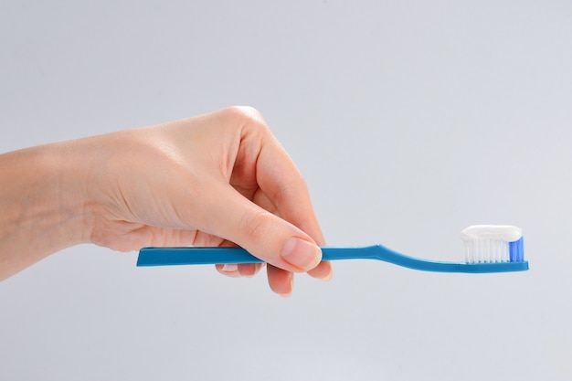 Woman holds toothbrush with toothpaste in her hand isolated on white background.