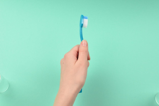 The woman holds toothbrushes in her hand on a green background