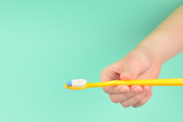 The woman holds toothbrushes in her hand on a green background