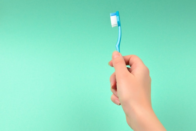 The woman holds toothbrushes in her hand on a green background