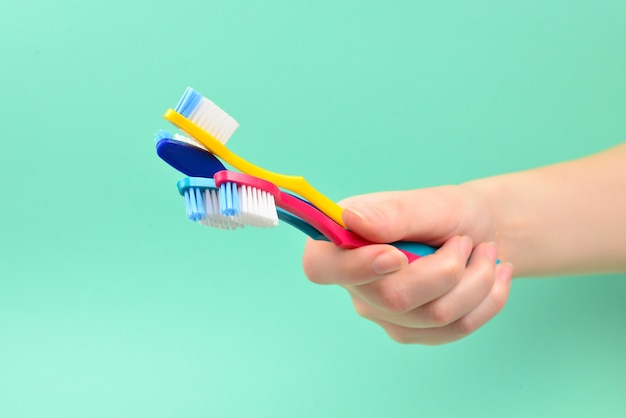 The woman holds toothbrushes in her hand