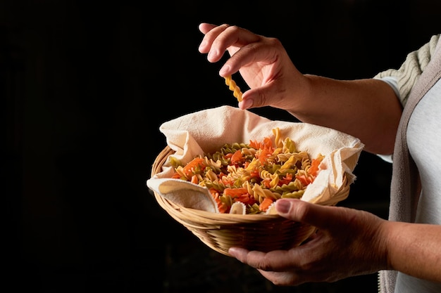 Woman holds tricolor fusilli pasta in a basket