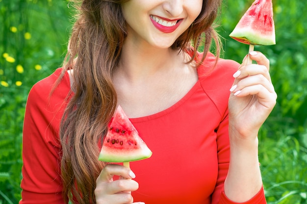 Woman holds two pieces of watermelon.