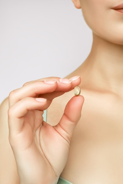 a woman holds a vitamin capsule in her hand taking vitamins and nutritional supplements concept