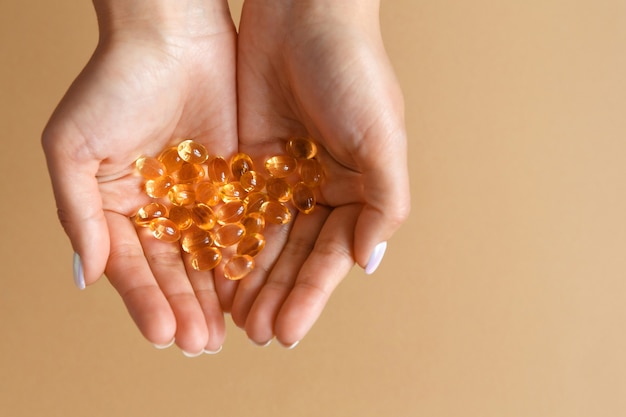 La donna tiene le capsule o le compresse di vitamina omega-3 nei palmi delle mani. il concetto di alimentazione sana e dieta