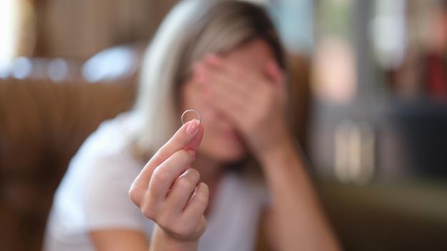 Woman holds wedding ring in hands and cries at home