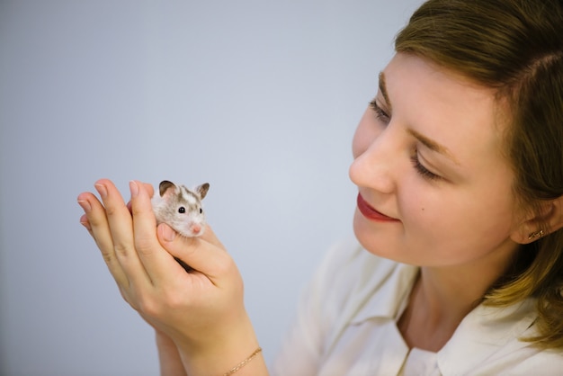 Woman holds white furry little mouse.