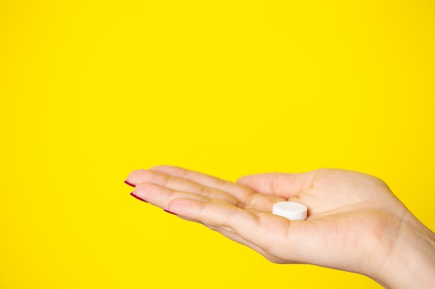 Woman holds white pill in her hand for weight loss