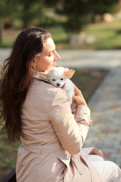 女性は白い子犬を持っています