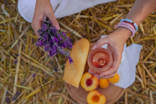 A woman holds wine in glasses. Picnic in the lavender field. Selective focus.