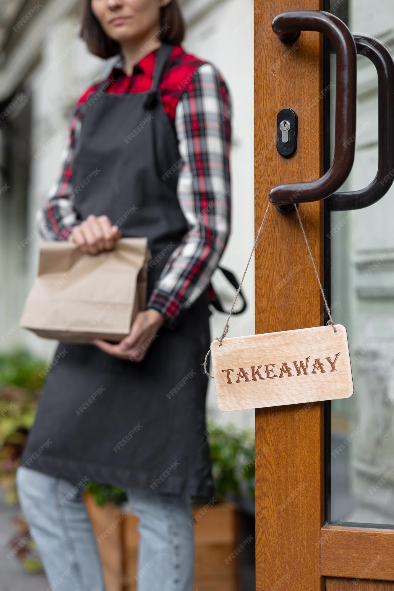 Premium photo woman holds a wooden sign with the inscription takeaway