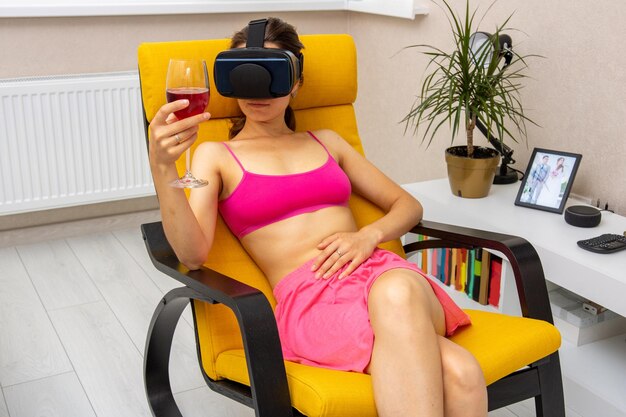 Photo woman at home in armchair with glass of wine and virtual glasses relaxes