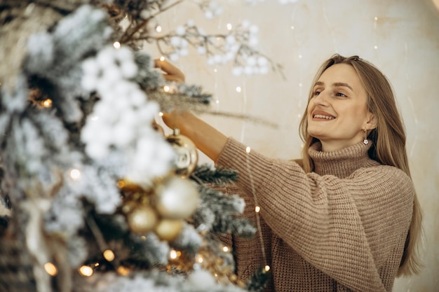 Woman at home by the christmas tree with presents