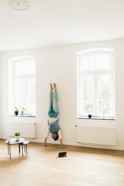 Woman at home doing a handstand at the wall