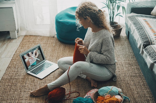 Foto donna a casa che lavora a maglia per hobby e attività ricreative da sola guardando il tutorial su lin