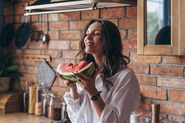 Woman at home eating watermelon in the kitchen