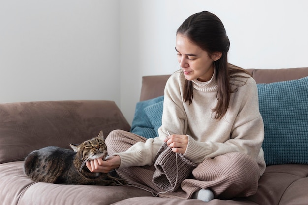 Foto donna a casa a lavorare a maglia e giocare con il gatto