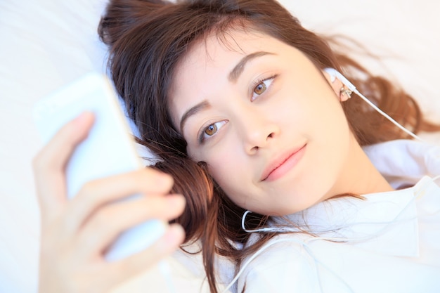 woman at home reading a text message from smartphone in her bright bedroom