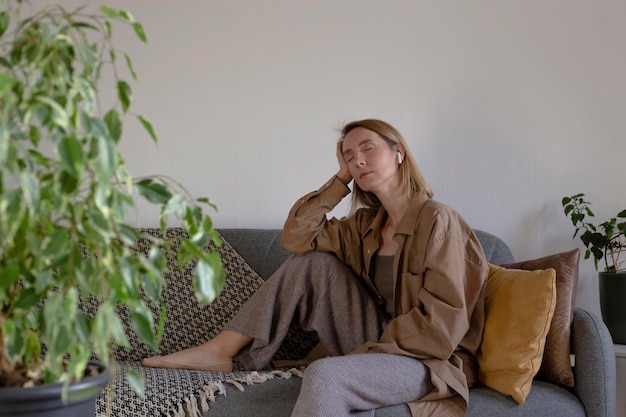 Женщина дома отдыхает и слушает медитацию на диване