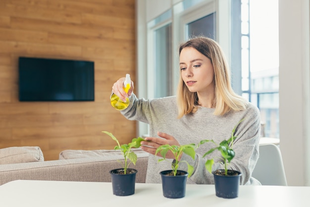 家の女性が植木鉢の世話をし、テーブルに座って花を注ぐ