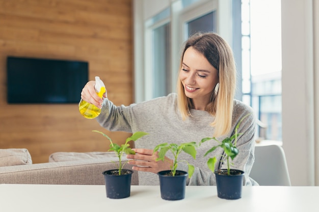 家の女性が植木鉢の世話をし、テーブルに座って花を注ぐ