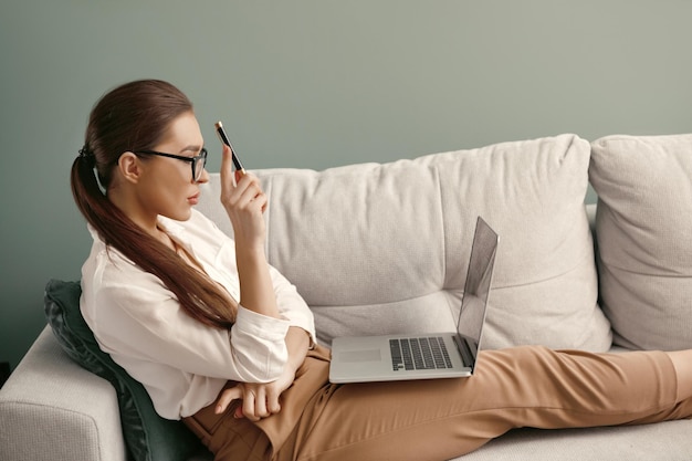 Woman at home using laptop sitting on sofa online working at home