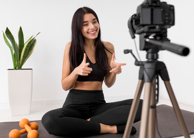 Woman at home vlogging with camera while exercising