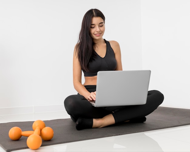 Woman at home vlogging with laptop and weights