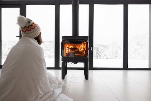 Woman at home with burning fireplace during wintertime on nature