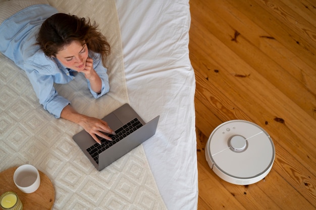 Woman at home with robotic wireless vacuum cleaner