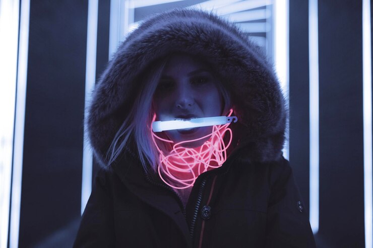 Photo woman in hooded clothing carrying equipment in mouth standing against illuminated lights